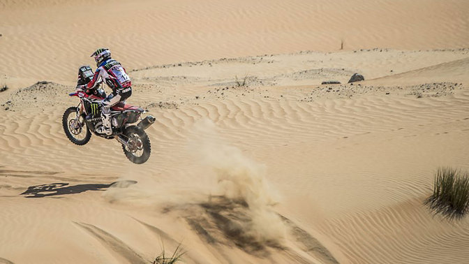 Háromnegyedes, hátulról készült felvétel egy homokdűnéken haladó Honda CRF450-ről.