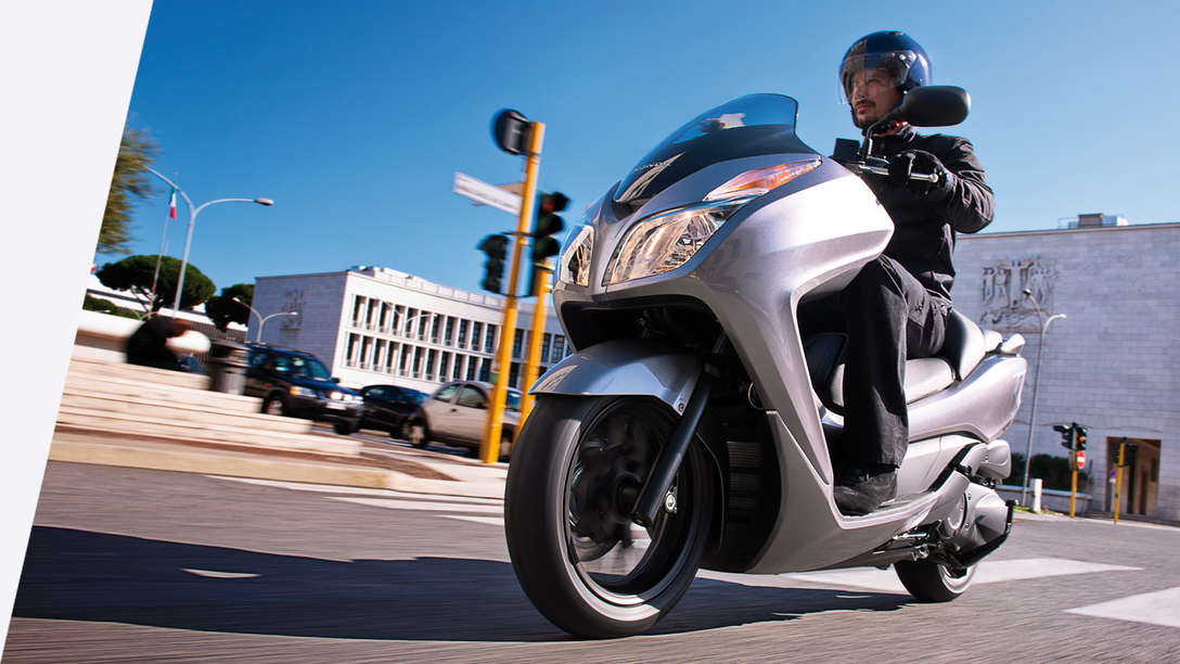 Egy Honda NSS300 Forza motorossal, háromnegyedes nézetben. Bal oldali profil (közúton).