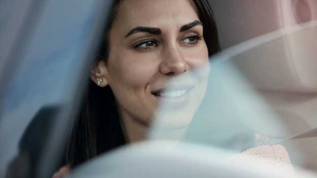 Közeli kép egy hölgyről, aki kinéz az autó lehúzott ablakán