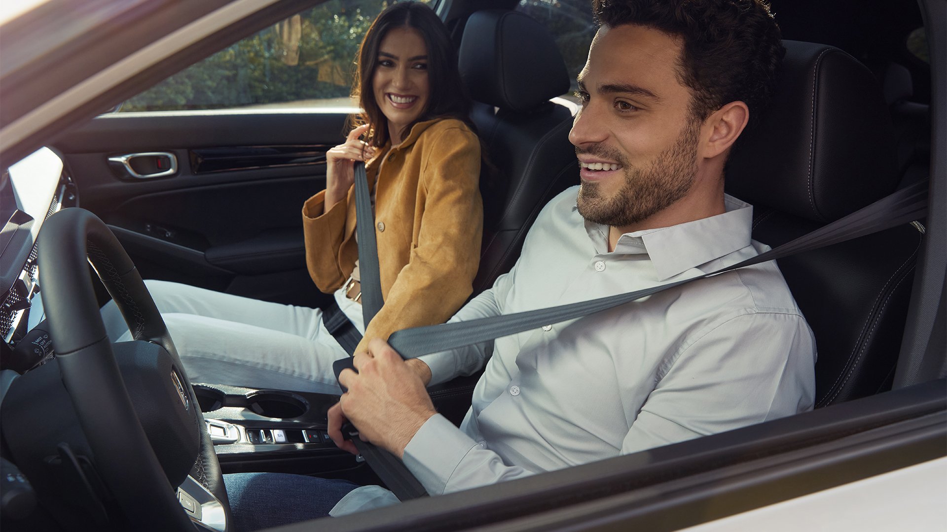Két ember bekapcsolja a biztonsági övét a Honda Civic Hybridben.