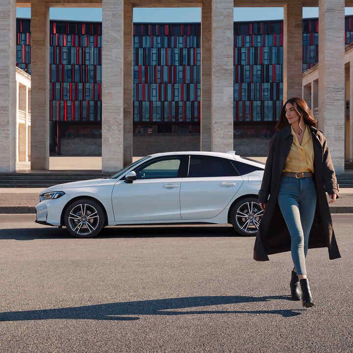 Hölgy sétál a Civic Hybrid előtt.