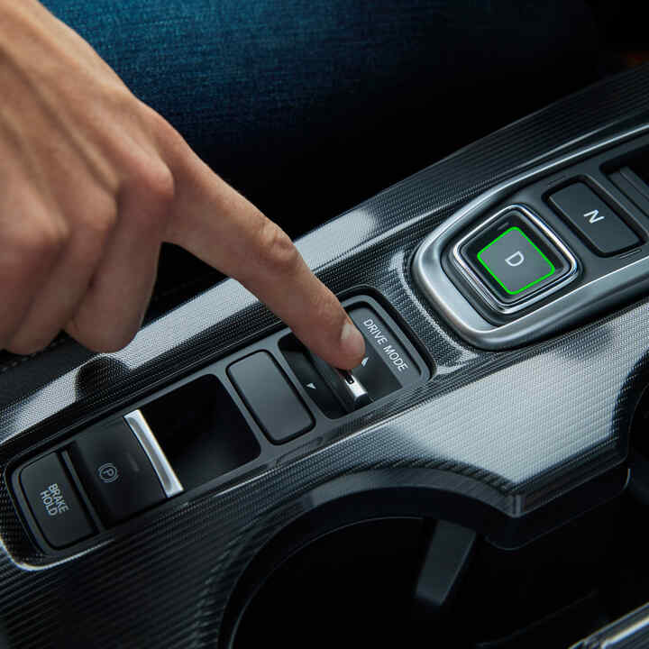 Közelkép egy személyről, aki a Civic Hybrid belsejében váltogatja a vezetési módokat.