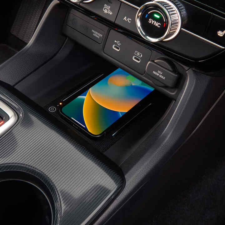 Közelkép egy vezeték nélkül töltődő telefonról a Civic Hybrid belsejében.