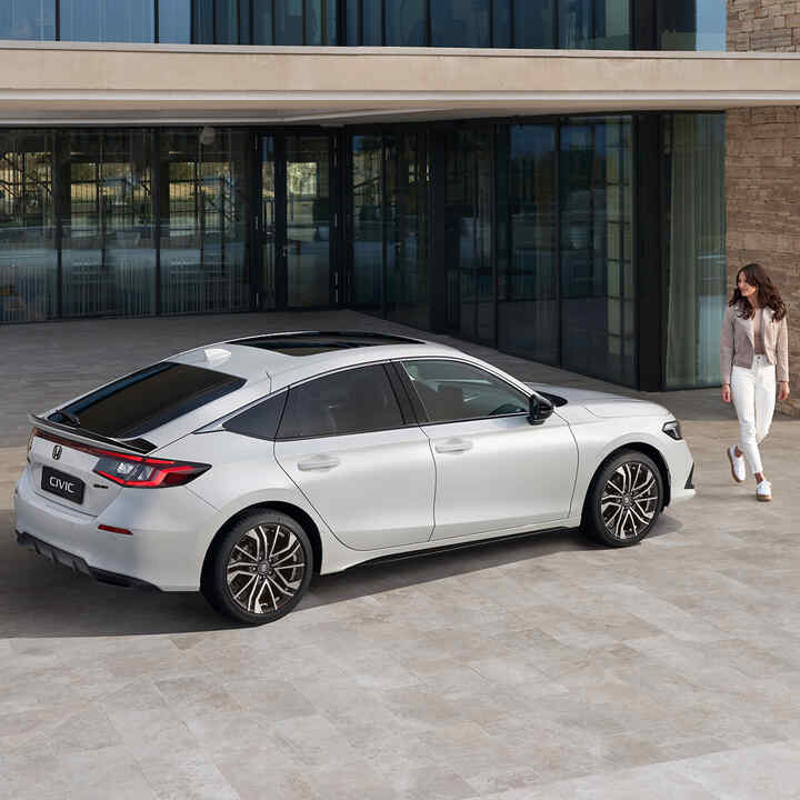 Egy parkoló Honda Civic e:HEV felé sétáló hölgy.