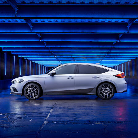 Oldalnézetből készült kép a Honda Civic e:HEV-ről, amely egy mellékutcában parkol.