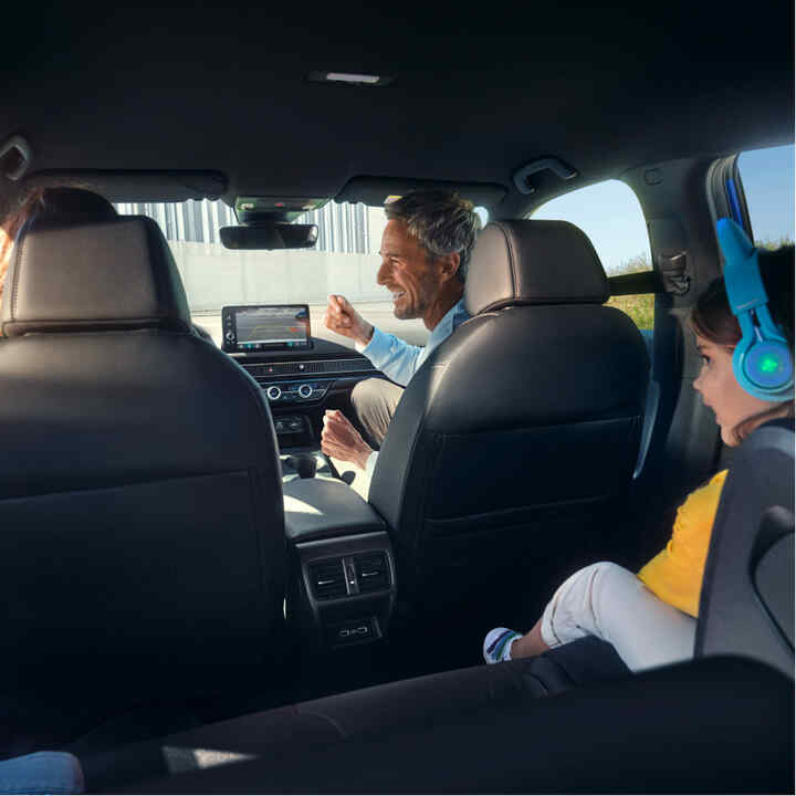 Felvétel a hátsó ülésekről, ahogy egy család ül az autóban. 