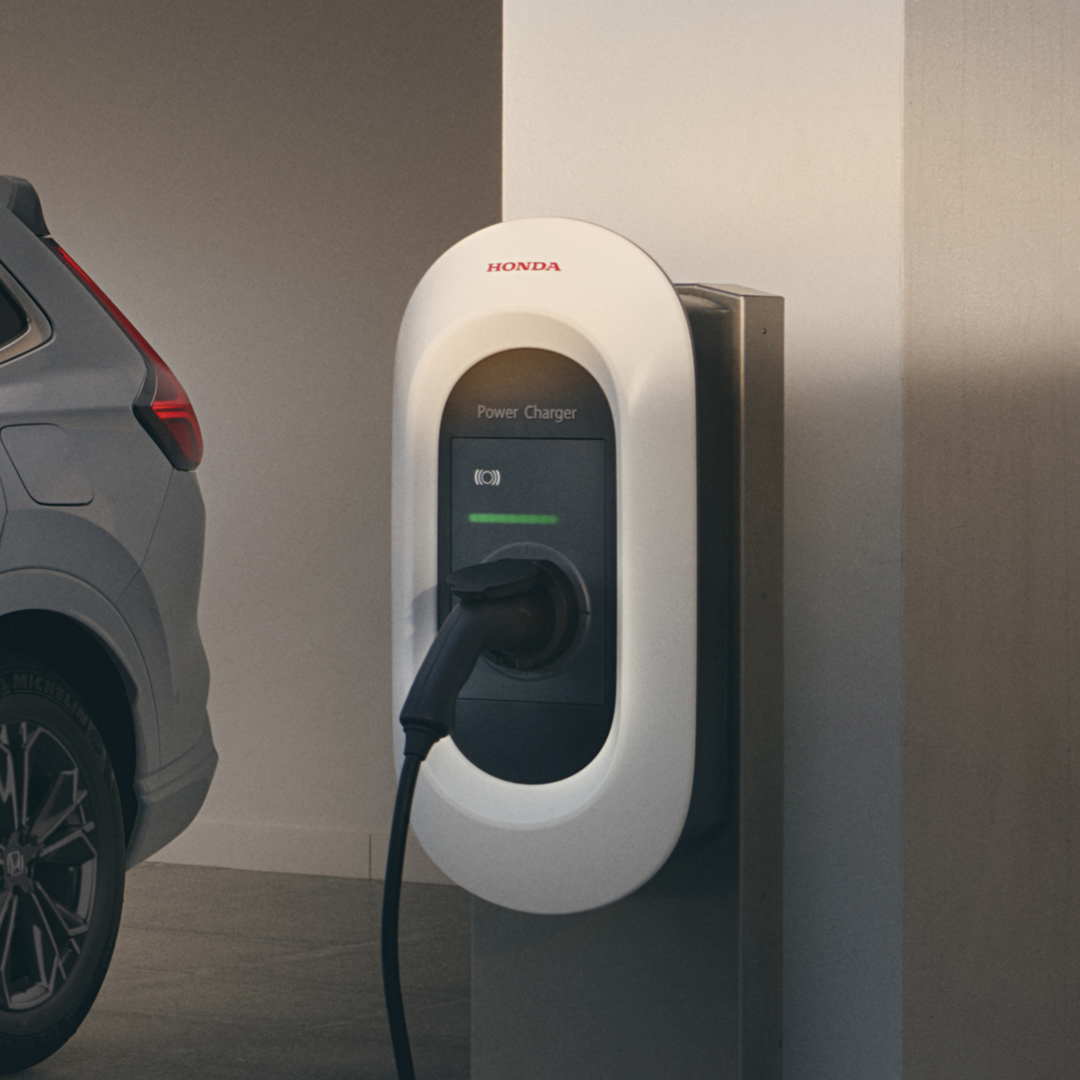 Háromnegyed-profilos elölnézeti kép a Honda CR-V Hybrid gépkocsiról töltés közben.