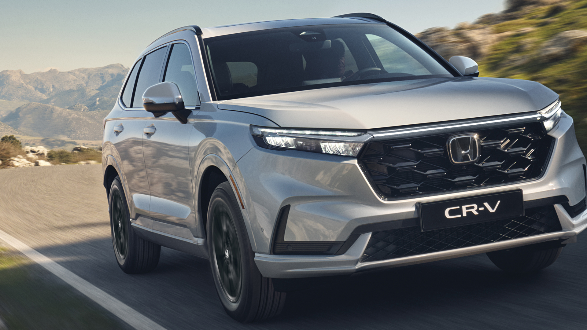 Háromnegyed-profilos elölnézeti kép a Honda CR-V Hybrid gépkocsiról hegyvidéki környezetben.