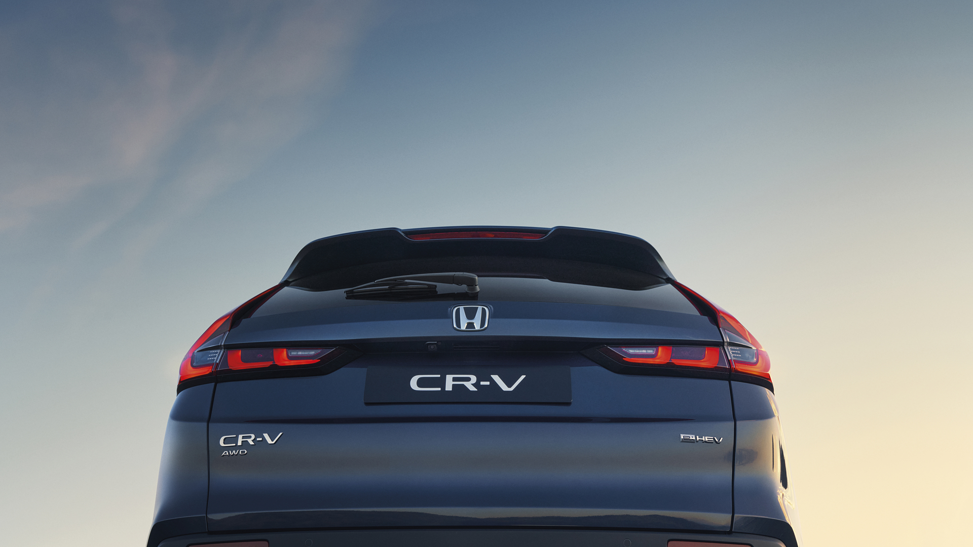 Rear view of a dark blue Honda CR-V SUV against a light sky background. The vehicle's distinctive taillights and CR-V badging are clearly visible on the tailgate.