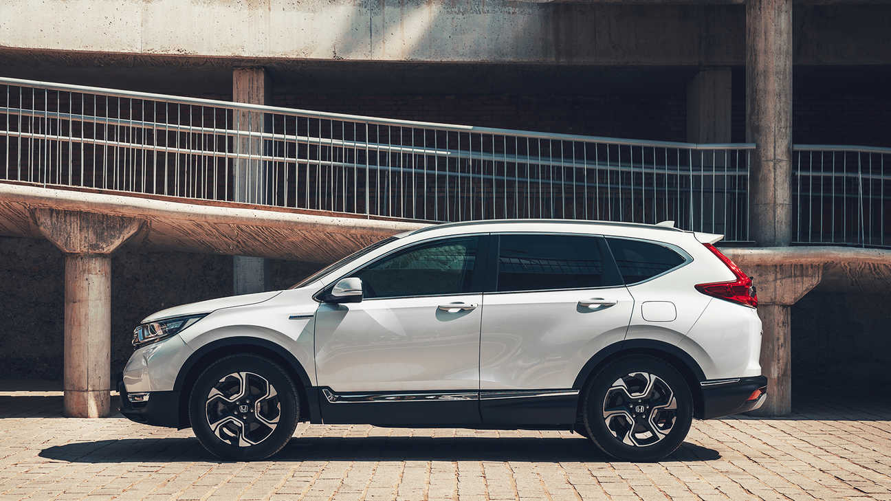 Oldalnézeti kép a Honda CR-V hibrid gépkocsiról utcai környezetben.