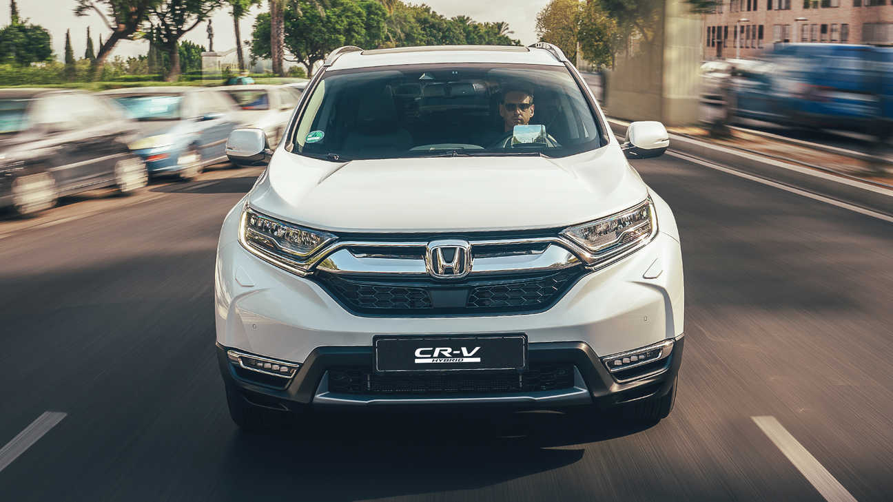 Elölnézeti kép a Honda CR-V hibrid gépkocsiról utcai környezetben.