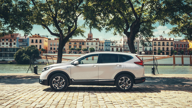 Oldalnézeti kép a Honda CR-V hibrid gépkocsiról utcai környezetben.