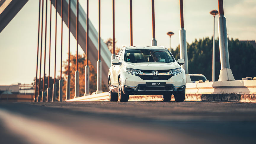 Háromnegyed-profilos elölnézeti kép a Honda CR-V hibrid gépkocsiról utcai környezetben.