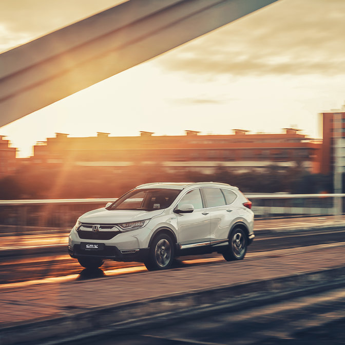 Oldalnézeti kép a Honda CR-V hibrid gépkocsiról utcai környezetben.