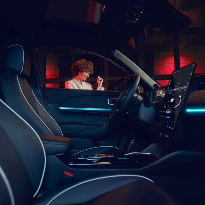 A Honda e:Ny1 megvilágított belső tere éjszaka, az ablakból egy modell látható.