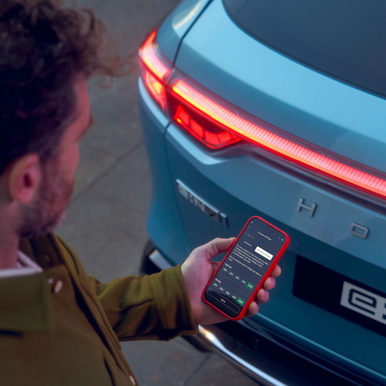 Egy férfi a Honda e:Ny1 mellől a My Honda Plus alkalmazást nézi