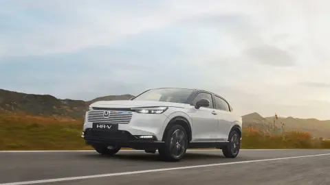 Elölről készült, háromnegyedes felvétel a Honda HR-V modellről, amely vidéki környezetben halad