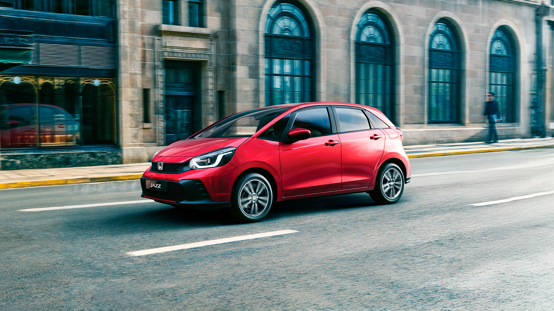 Elölről, háromnegyedes szögből készült felvétel a Honda Jazz modellről, amelyet városi környezetben vezetnek.