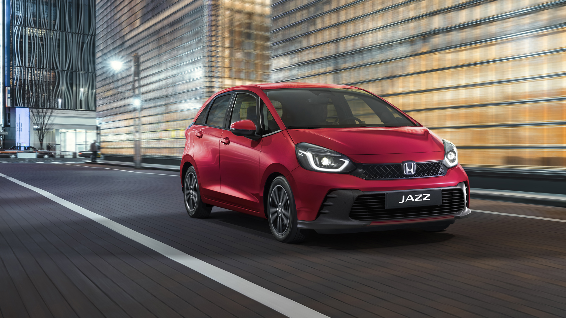 Elölről, háromnegyedes szögből készült felvétel a Honda Jazz modellről városi háttér előtt.