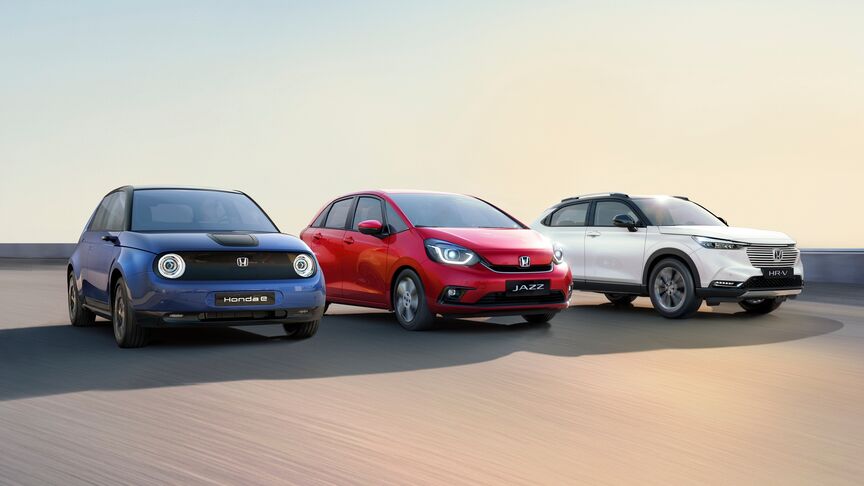 Egy fehér Honda e mellett álló hölgy, aki a My Honda Plus alkalmazást használja