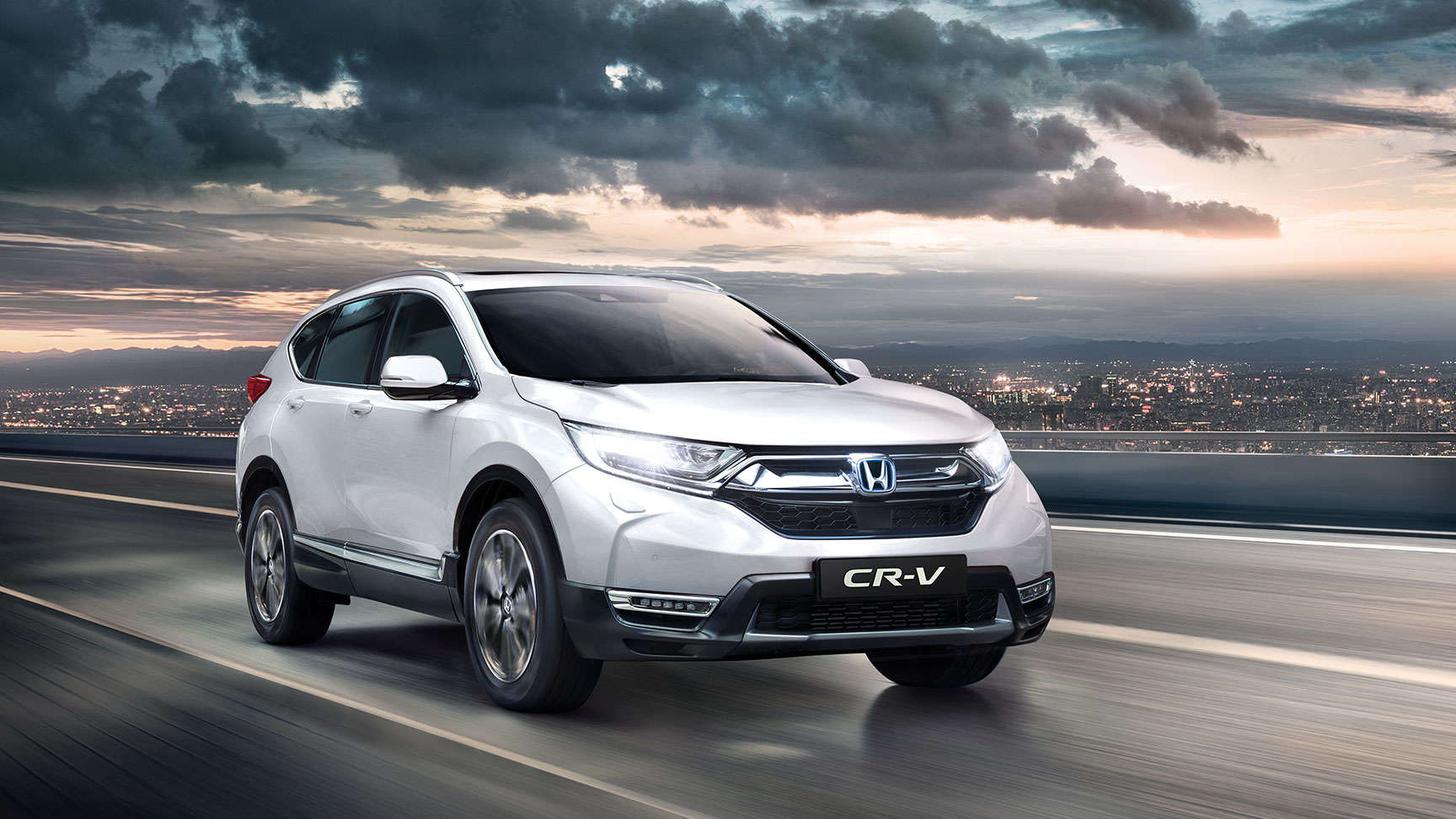 Háromnegyedes felvétel a Honda CR-V elejéről bekapcsolt távolsági fényszóróval