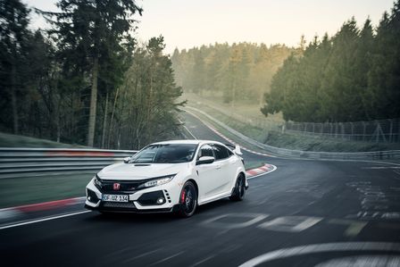 Elölről készül, háromnegyedes felvétel a Nürburgringen haladó Honda Civic Type R-ről.