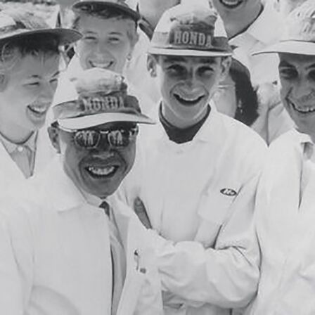 Soichiro Honda és a gyár alkalmazottjai fehér munkaruhában.