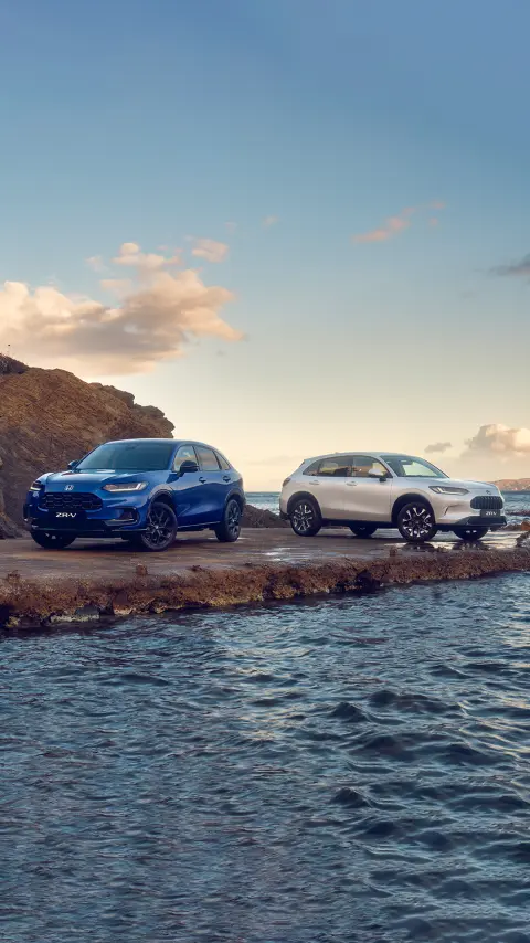 Két előre néző ZR-V hibrid háromnegyedes nézetben, ahogy a hegyekben parkolnak.