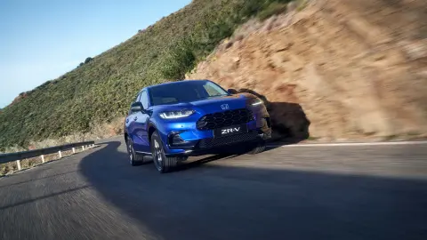 Egy hegyvidéki környezetben, közúton vezetett Honda ZR-V hibrid SUV.