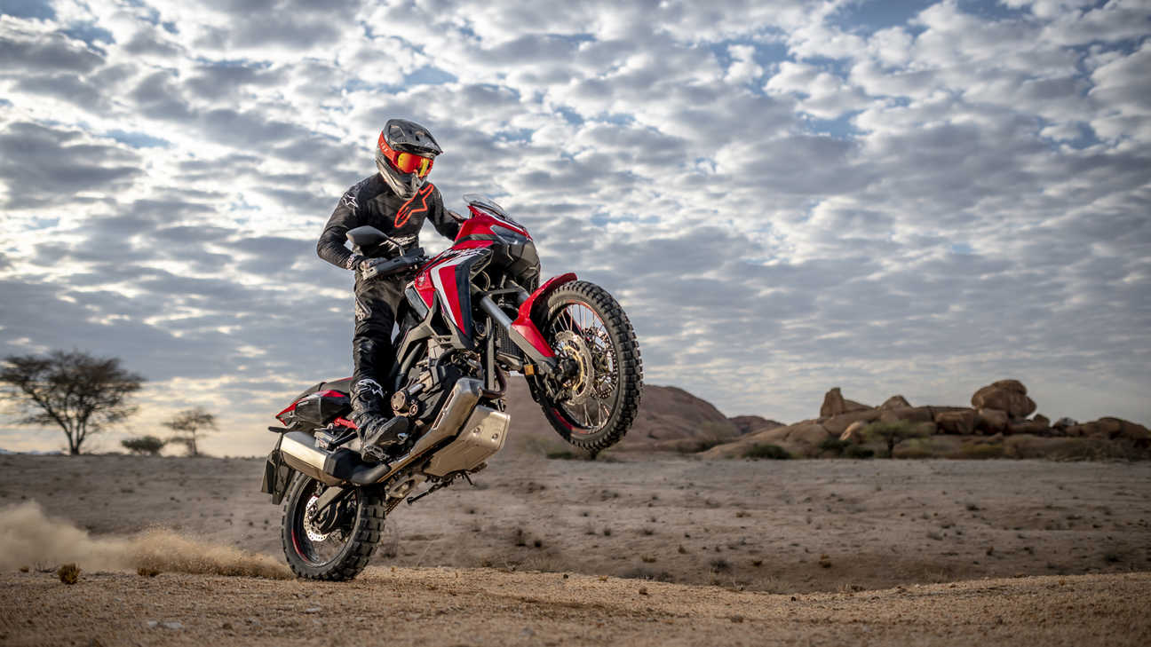 Honda Africa Twin, háromnegyedes, jobbról elölről készült felvétel sivatagi környezetben egykerekezés közben