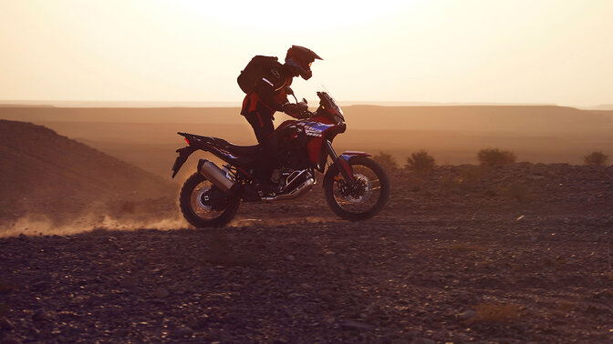 Fotómodell ül egy CRF1100L Africa twin motorkerékpáron a sivatagban.