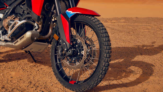 Egy sivatagi környezetben lefényképezett CRF1100L Africa Twin motorkerékpár kerekeinek közelképe.