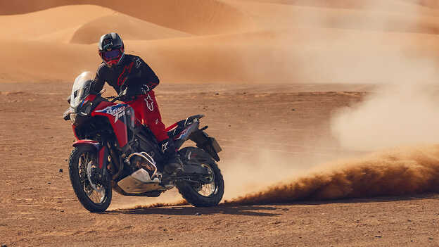 Fotómodell vezet egy CRF1100L Africa Twin motorkerékpárt a sivatagban.
