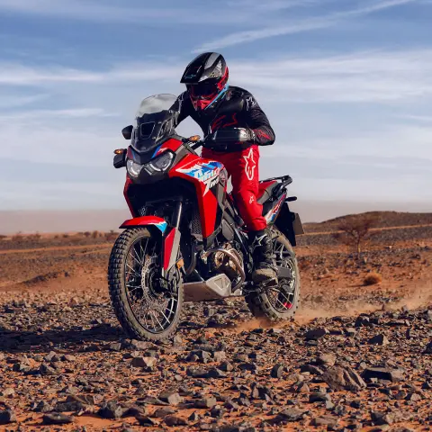 Fotómodell vezet egy CRF1100L Africa Twin motorkerékpárt a sivatagban, köves-sziklás terepen.
