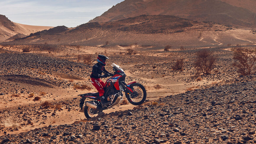 Fotómodell halad egy CRF1100L Africa Twin motorkerékpárral a sivatagban.