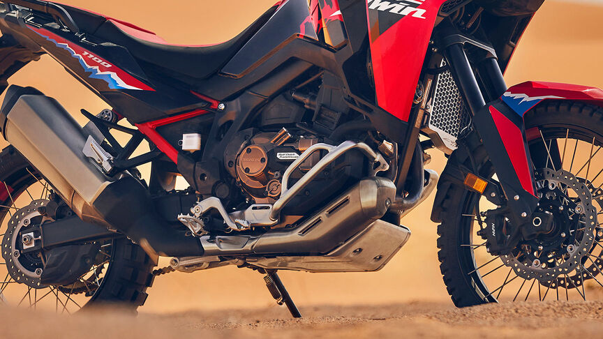 Fotómodell halad egy CRF1100L Africa Twin motorkerékpárral a sivatagban.