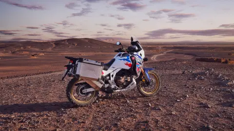 Motoros a Honda CRF1100 Africa Twin Adventure Sports nyergében, sivatagi környezetben.