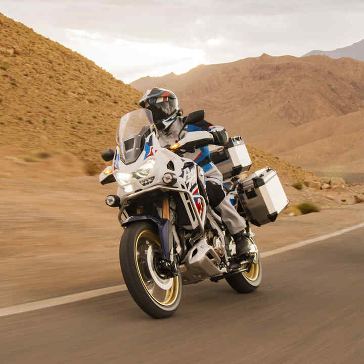 Motoros a Honda CRF1100 Africa Twin Adventure Sports nyergében, sivatagi környezetben.