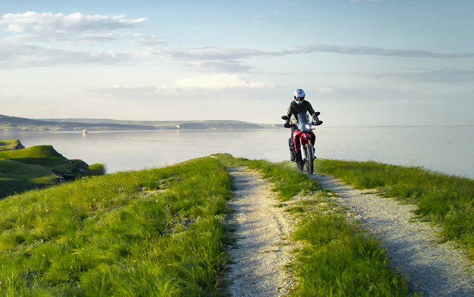 Egy CRF250 Rally jobb oldalról pilótával egy tengerparti úton