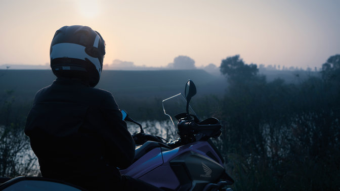 A Honda NC750X vidéki környezetben parkolva, rajta a pilótával.