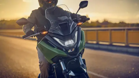 Elölről készült kép egy modellről, amint az NC750X motorkerékpárral közlekedik az úton.