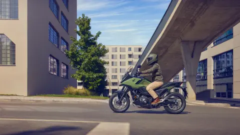 Oldalról készült felvétel a NC750X motorkerékpáron utazó modellről egy városi helyszínen.
