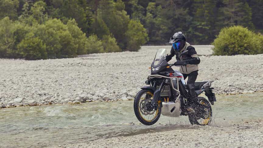 Modell vezet egy XL750 Transalp motorkerékpáron erdei környezetben.