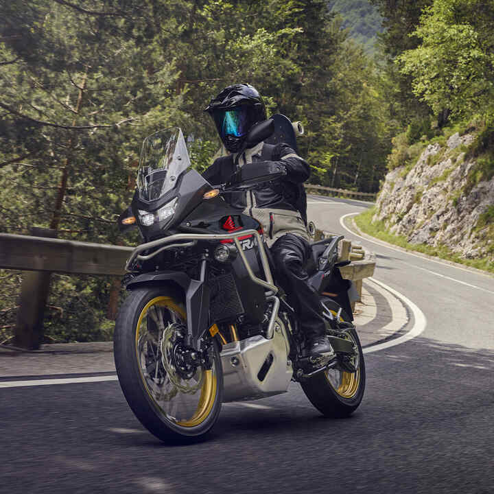 Modell az XL750 Transalp motorkerékpárral egy hegyvidéki helyszínen.