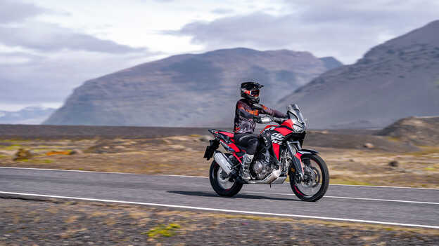 Az Africa Twin szemből, háromnegyedes nézetben, motorossal, közúton