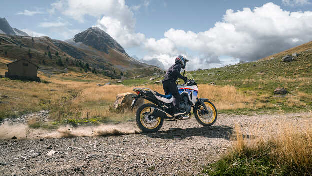 Transalp – dinamikus felvétel hátulról, kavicsos talajon, motorossal