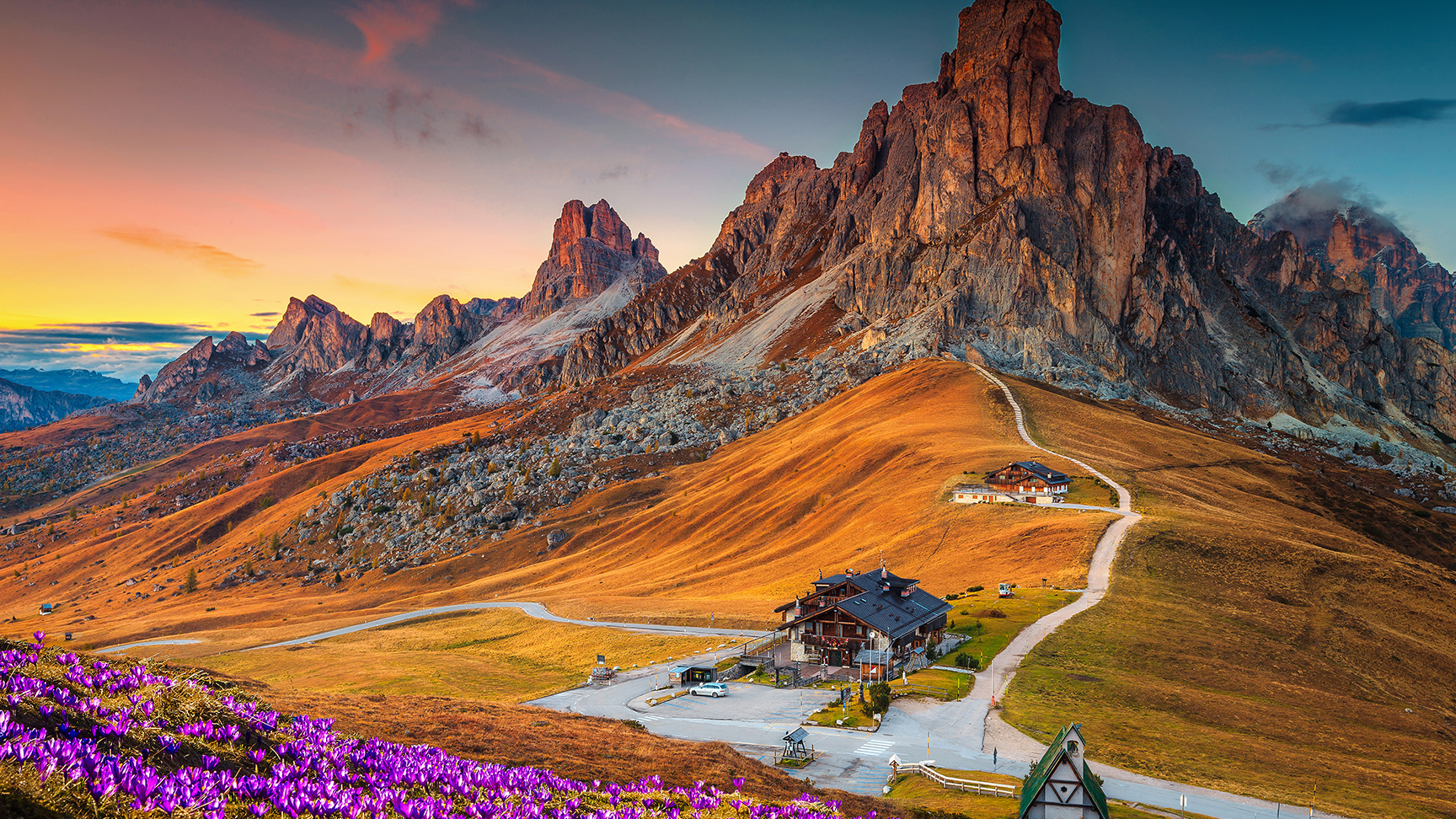 Csodálatos alpesi tájkép tavasszal nyíló krókuszok borította dombokkal és naplementében ragyogó festői hegyekkel, Giau-hágó, Dolomitok, Olaszország, Európa