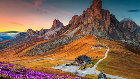 Csodálatos alpesi tájkép tavasszal nyíló krókuszok borította dombokkal és naplementében ragyogó festői hegyekkel, Giau-hágó, Dolomitok, Olaszország, Európa