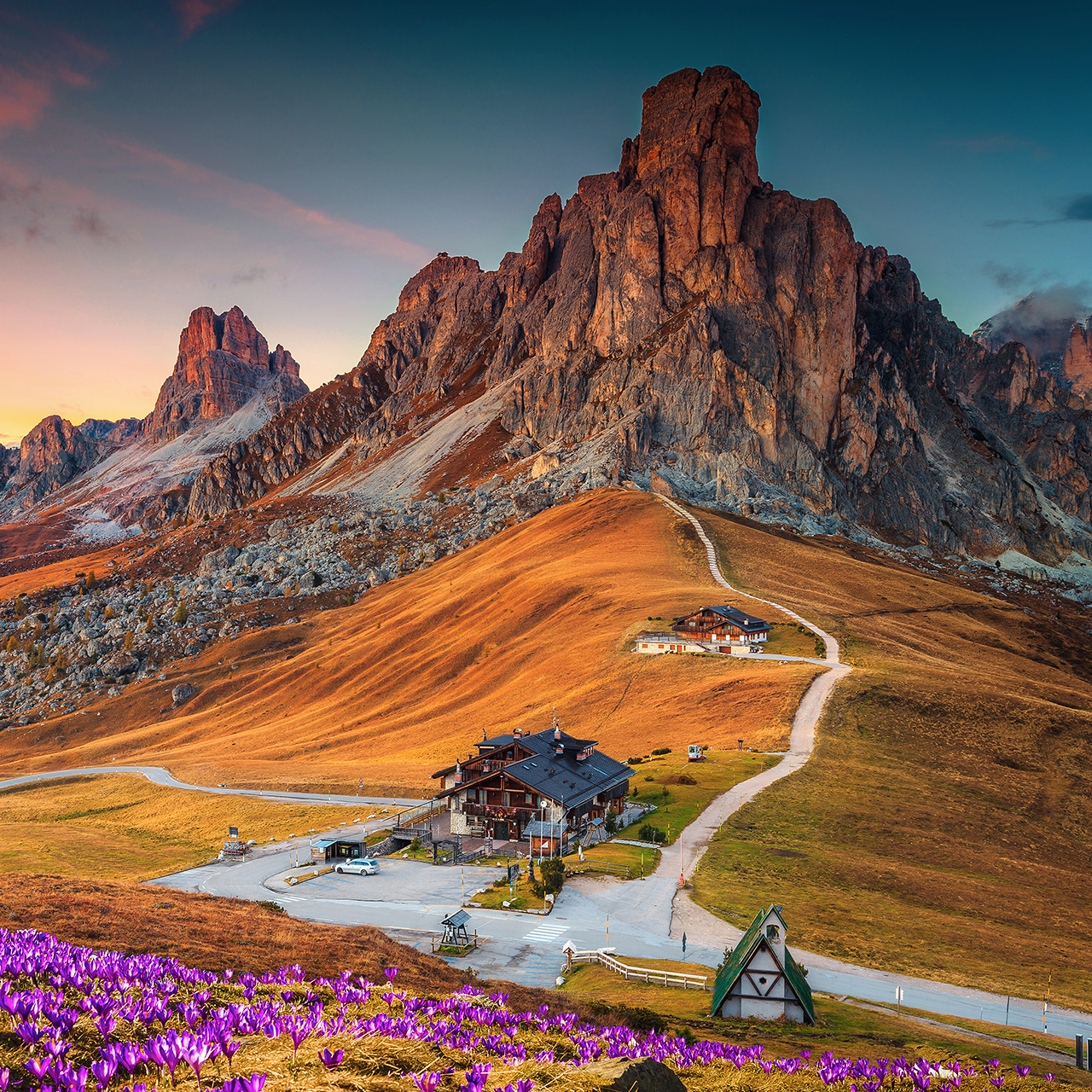 Csodálatos alpesi tájkép tavasszal nyíló krókuszok borította dombokkal és naplementében ragyogó festői hegyekkel, Giau-hágó, Dolomitok, Olaszország, Európa