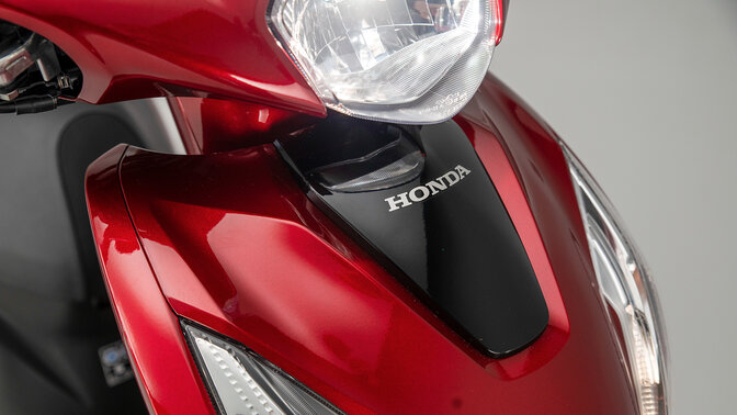 Közeli felvétel a Honda Vision 110 első burkolatáról és fényszóróiról